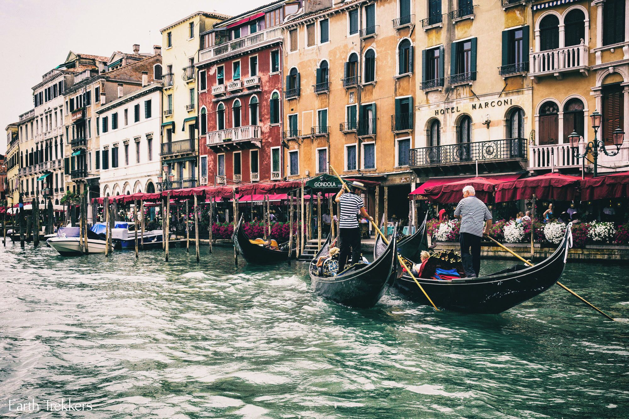 Gondolas on a canal in Venice, Italy, with colorful buildings and shops along the water.