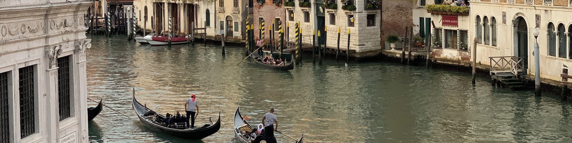 A canal with gondolas, historic buildings, and a clock tower in Venice.