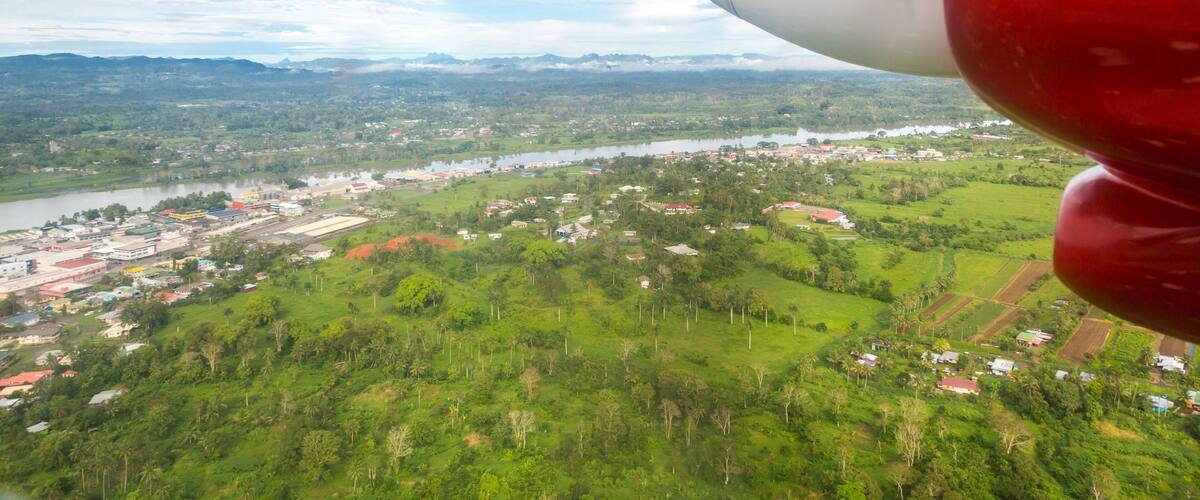 A red airplane engine with a view of a river, town, and green landscape.