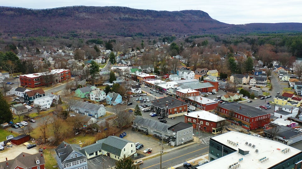 A town with a mix of residential and commercial buildings, a main street, and a backdrop of hills.
