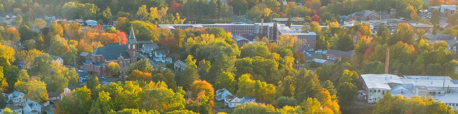 Aerial view of the vibrant foliage reflecting in the still waters of the pond, surrounded by the town's buildings, Easthampton, Massachusetts, United States.