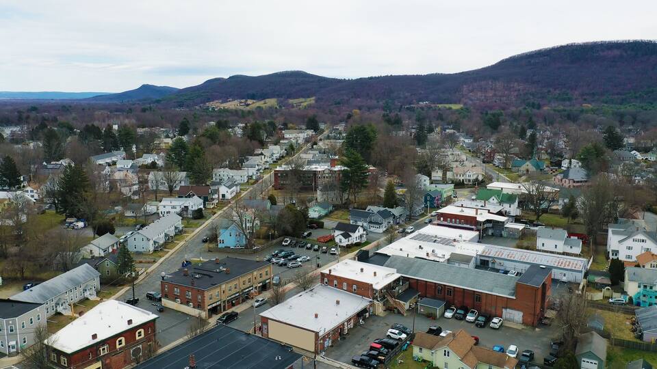 A town with a mix of residential and commercial buildings, surrounded by hills and mountains.