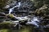 A waterfall cascading over rocks in a forested area.