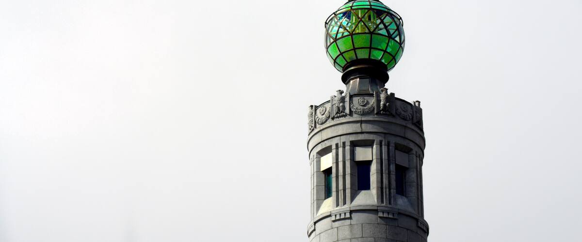 A tower with a green glass dome and intricate carvings.