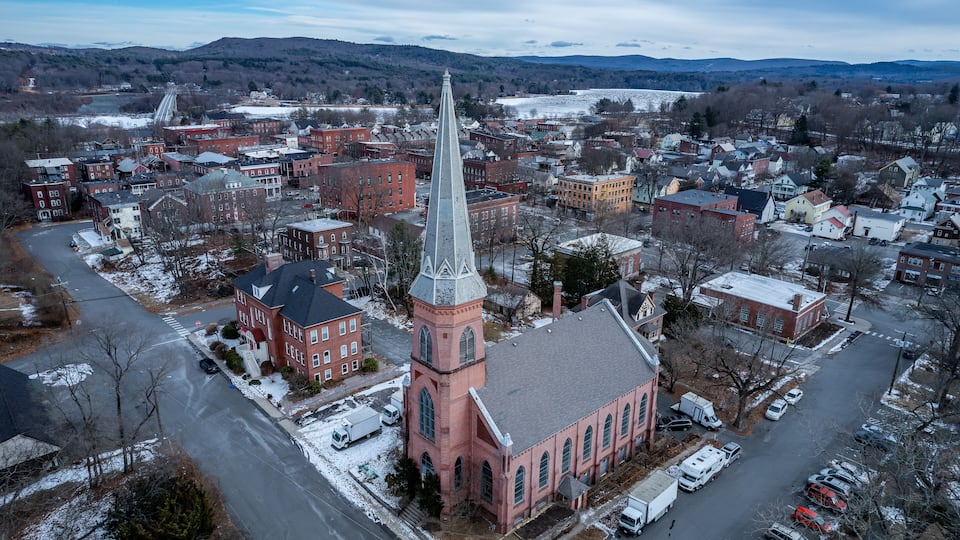 A town with a prominent church featuring a tall steeple, surrounded by residential buildings and a snow-covered landscape.