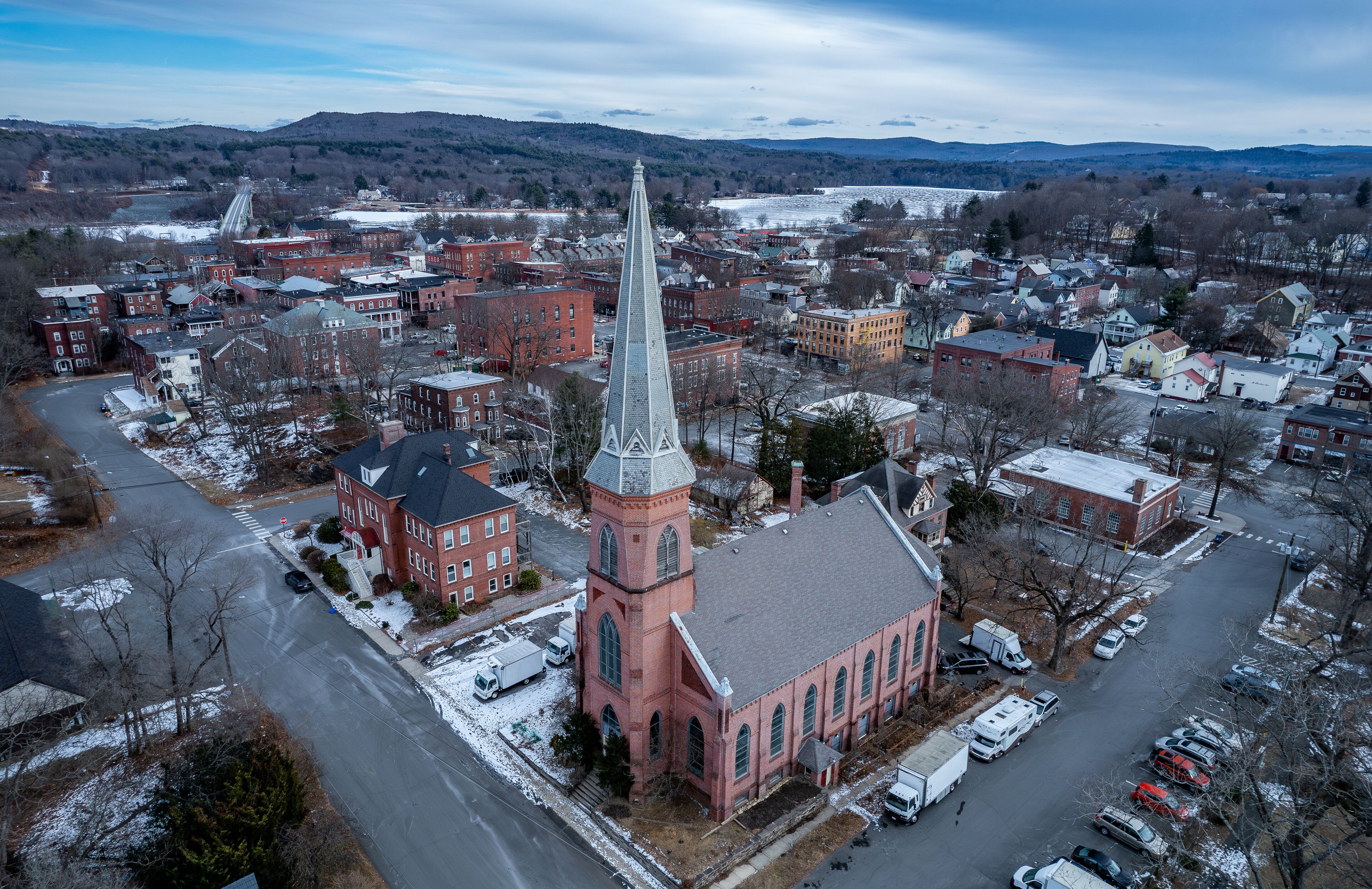 A town with a prominent church featuring a tall steeple, surrounded by residential buildings and a snow-covered landscape.
