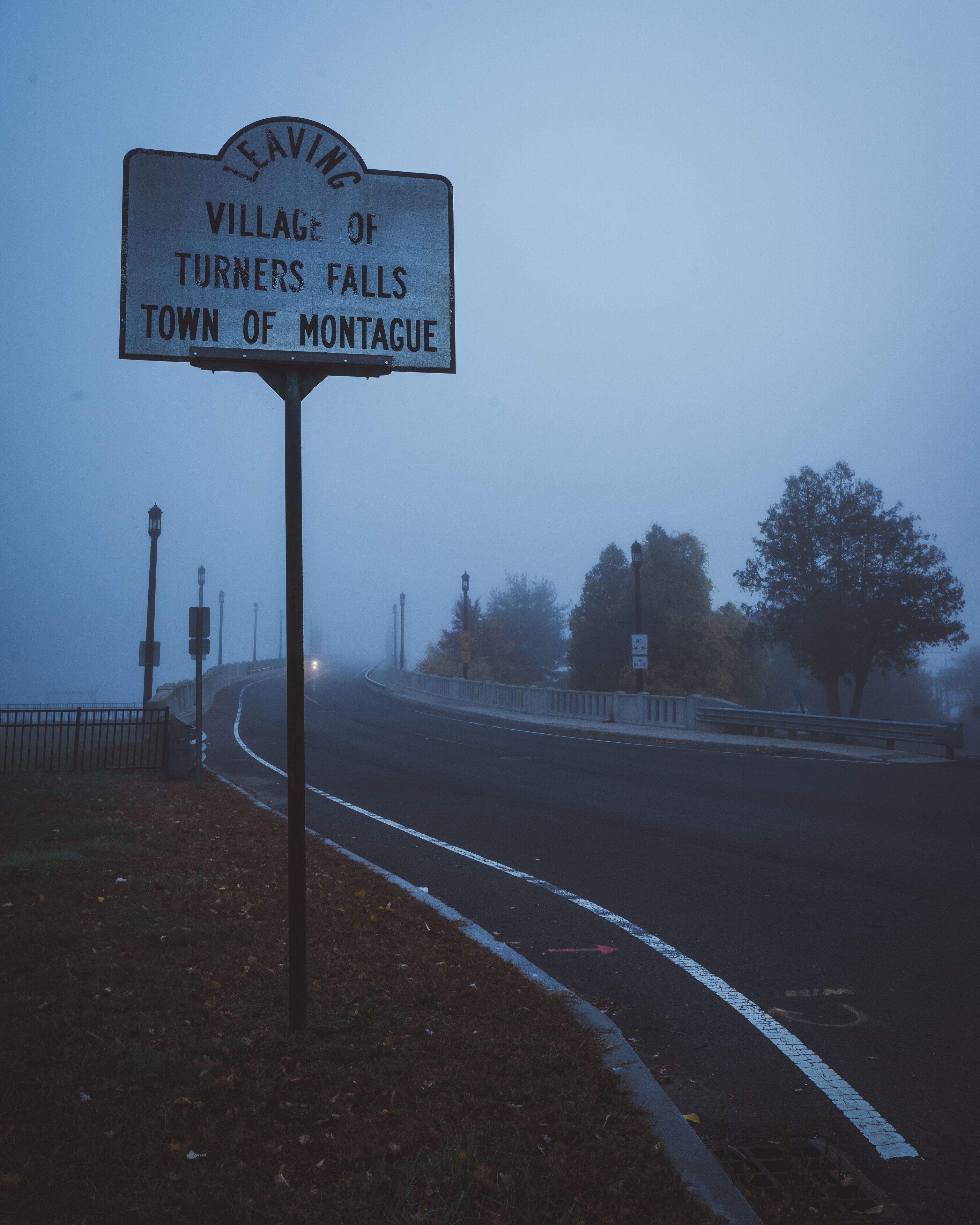 A foggy road with a sign for the Village of Turners Falls, Town of Montague.