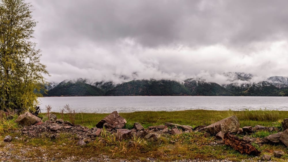 A lake with mountains in the background and a cloudy sky.