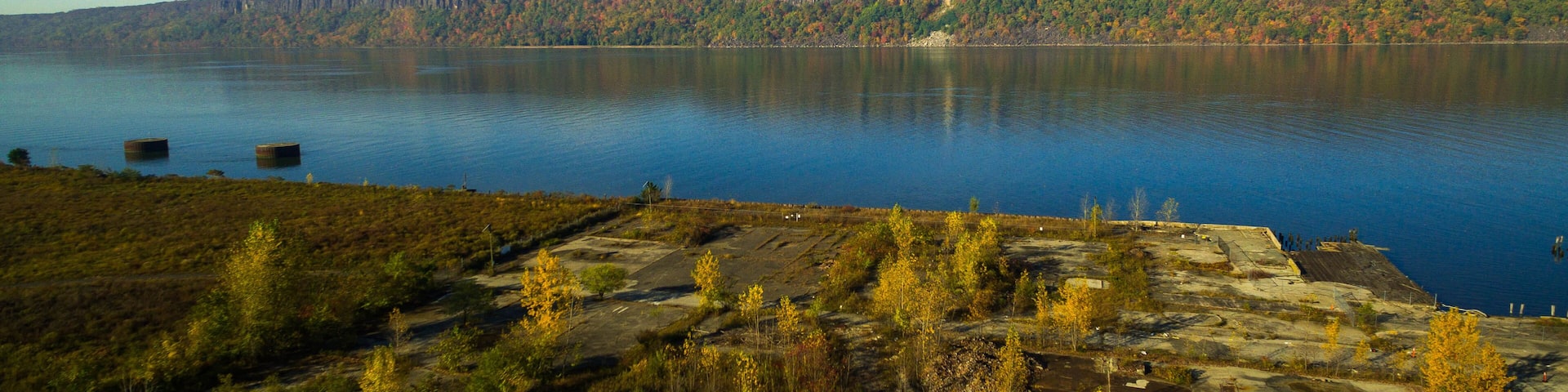 A calm lake with a forested cliff in the background.