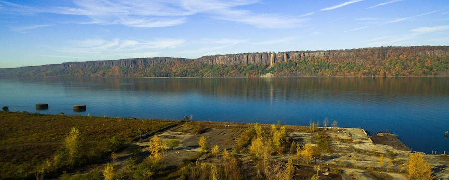 A calm lake with a forested cliff in the background.