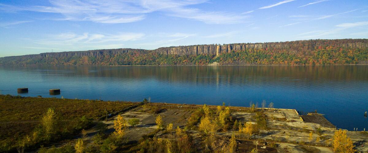 A calm lake with a forested cliff in the background.