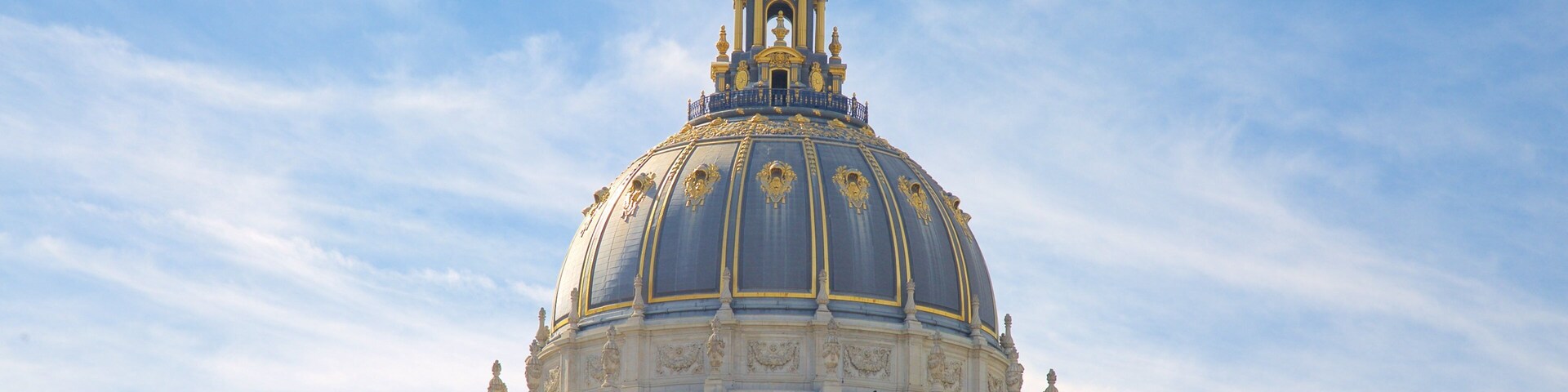 Um grande edifício em cúpula com detalhes dourados elaborados e uma bandeira.