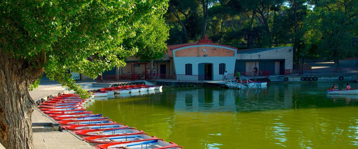 A row of red and white rowboats docked along a tree-lined waterfront.