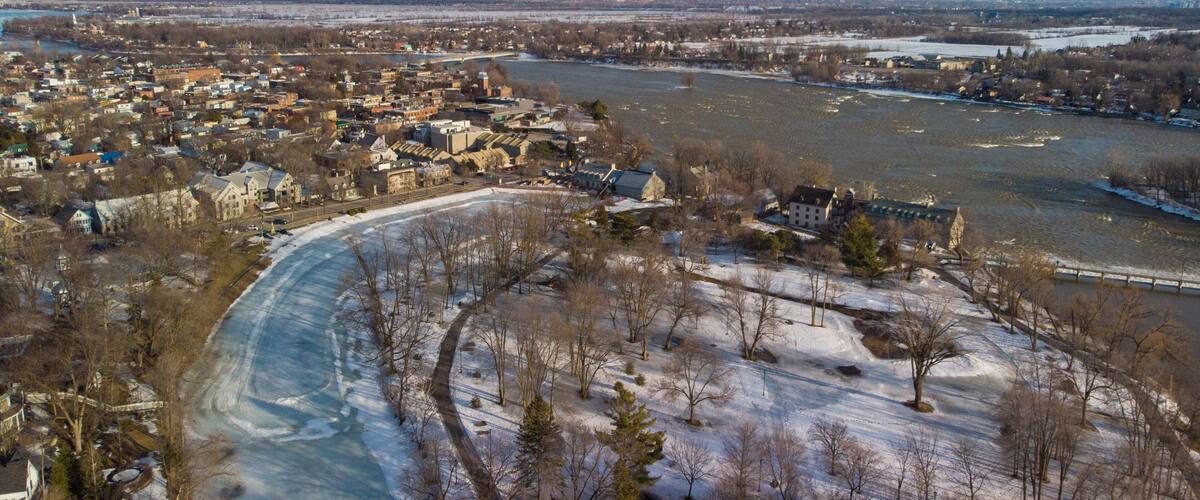 A river winding through a town with snow-covered ground and trees.
