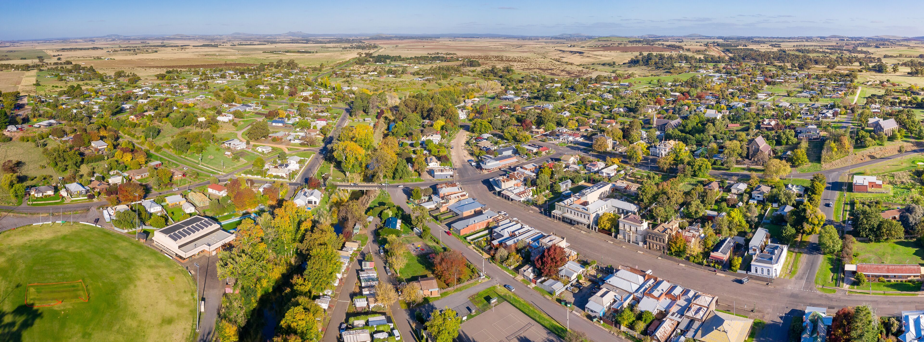 An aerial view of a suburban area with houses, roads, and green spaces.