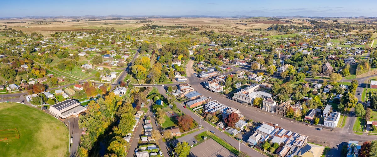 An aerial view of a suburban area with houses, roads, and green spaces.