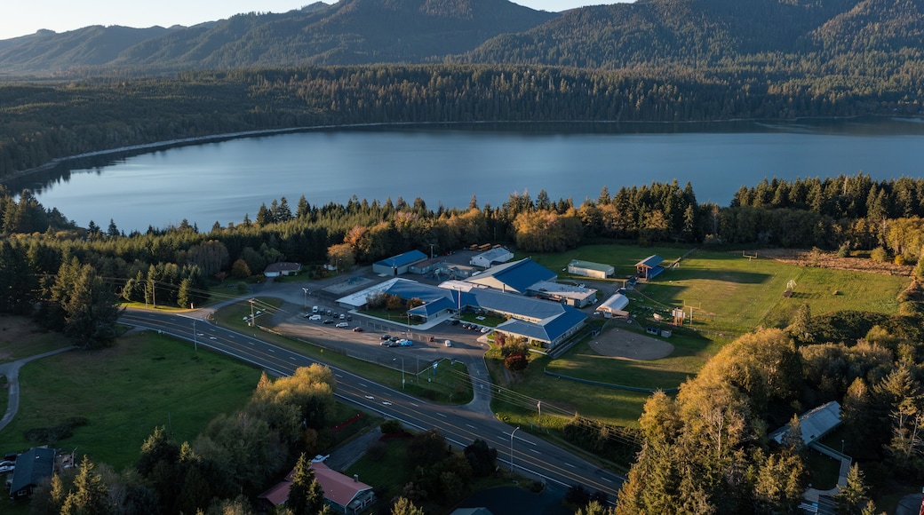 Aerial drone picture of Lake Quinault School District area in Amanda Park, Washington State USA, captured at sunset with warm fall golden light over surrounding evergreen forests and rural landscape