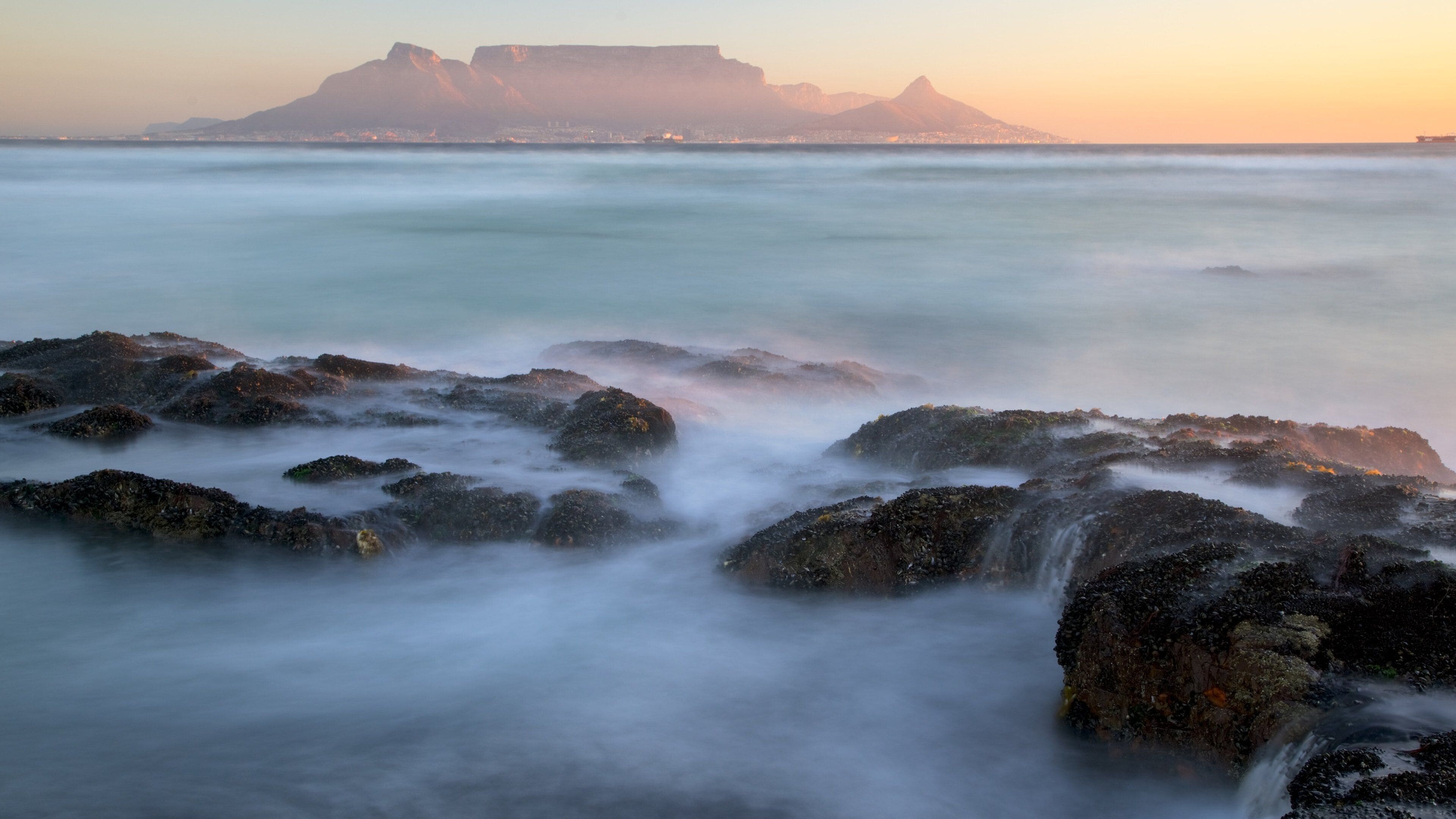 Bloubergstrand which includes mountains, a sunset and surf