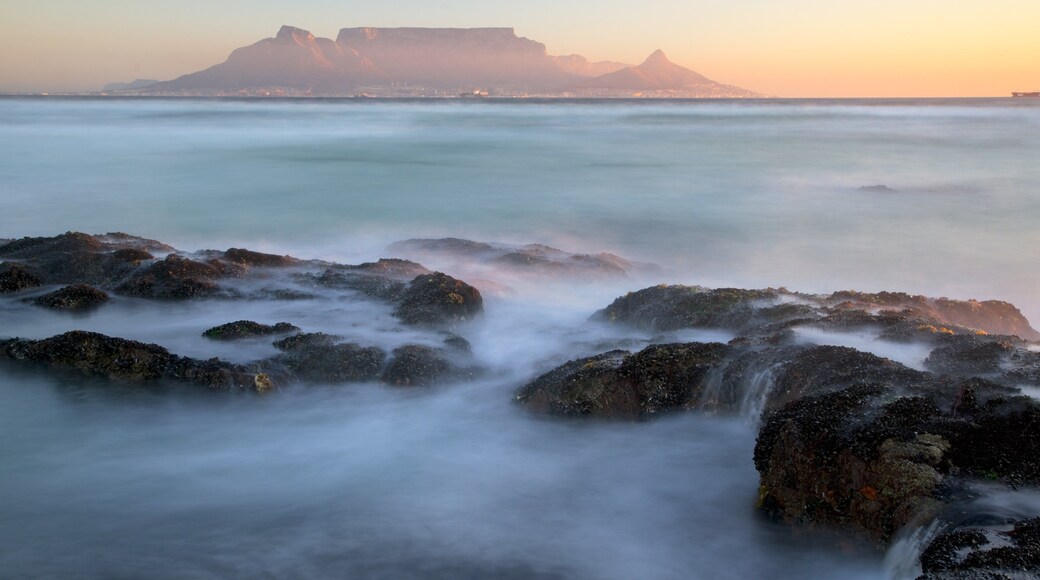 Bloubergstrand which includes mountains, a sunset and surf
