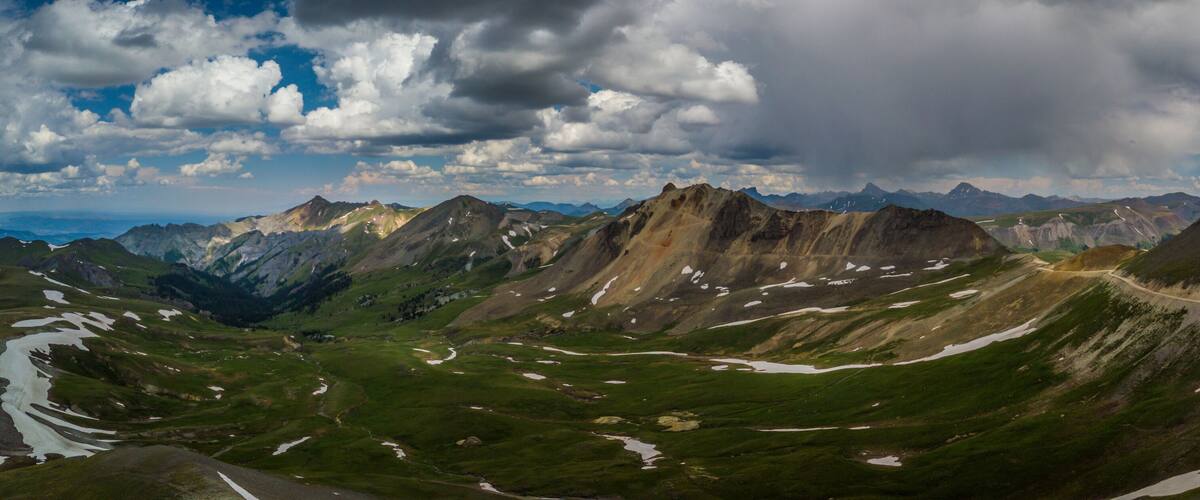 A mountainous landscape with a winding road and patches of snow.