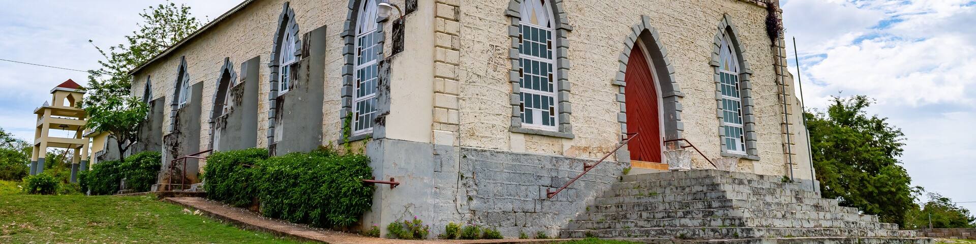 Vintage brick/ concrete wall chapel with red front door and stained glass windows in the countryside. Duncans Methodist Church in Trelawny parish, Jamaica, built in AD 1882.
