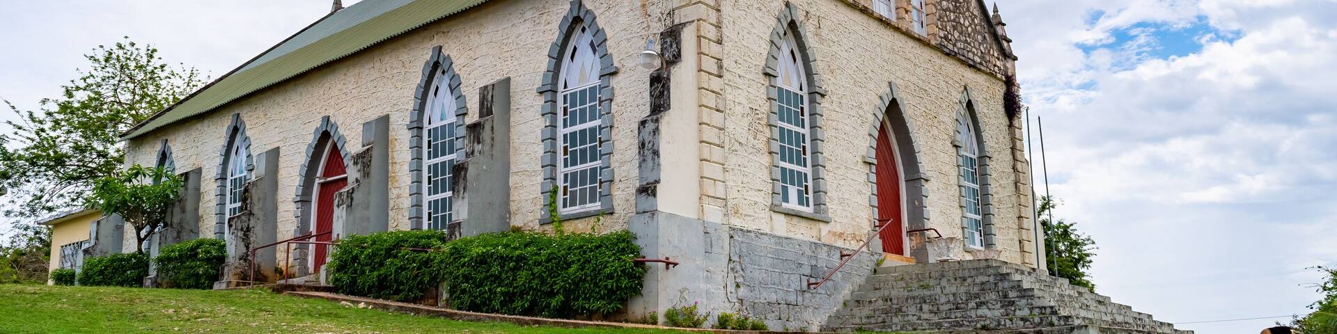 Vintage brick/ concrete wall chapel with red front door and stained glass windows in the countryside. Duncans Methodist Church in Trelawny parish, Jamaica, built in AD 1882.