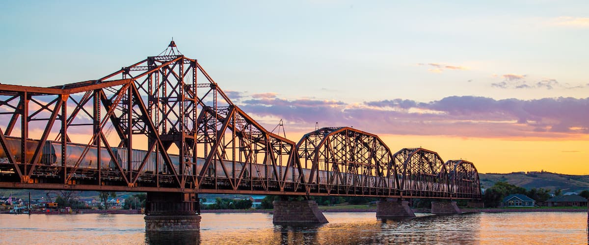 Un puente de acero sobre un río al atardecer.