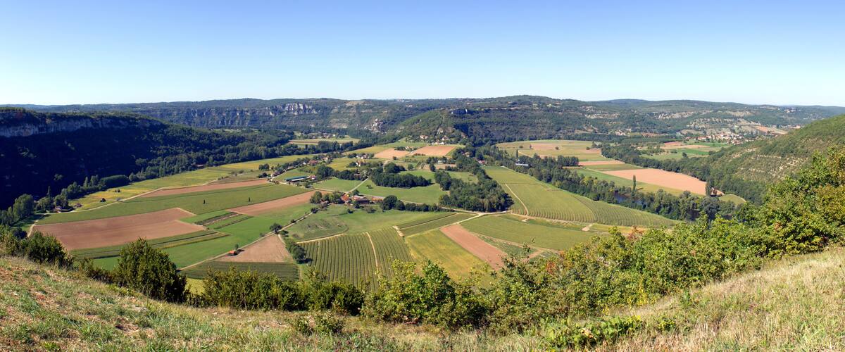 The view over patchwork fields and farms encircled by the River Lot. From Saut de la Mounine viewpoint near Cajarc, Lot, Quercy, France. Stitched panorama.