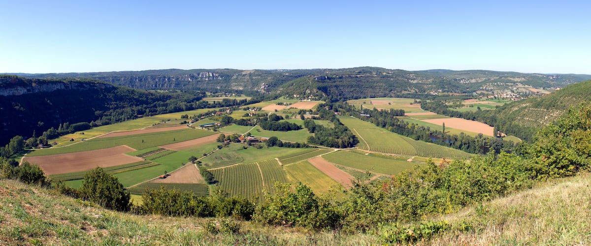 A valley with terraced fields, a river, and distant hills.