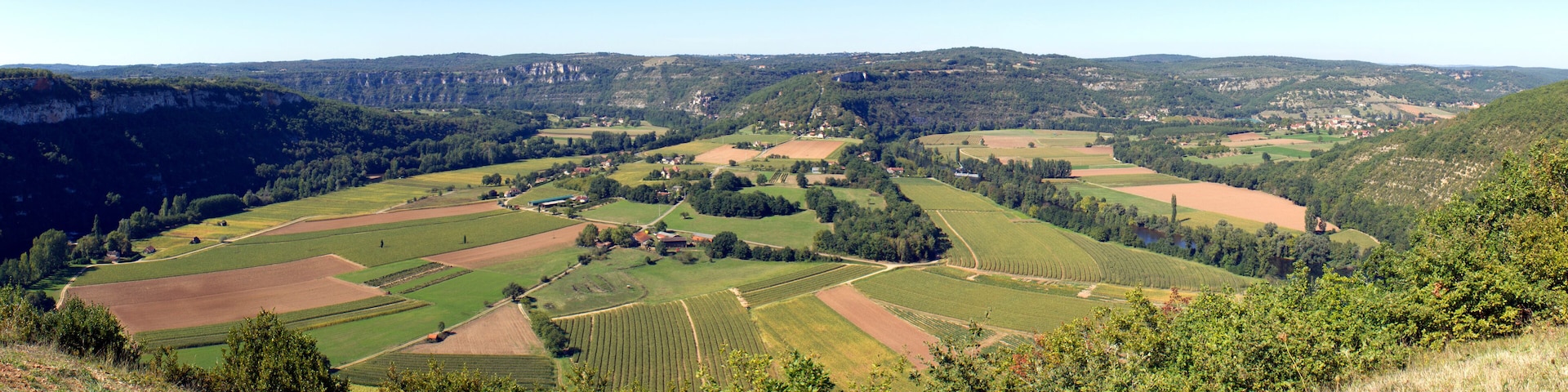 A valley with terraced fields, a river, and distant hills.