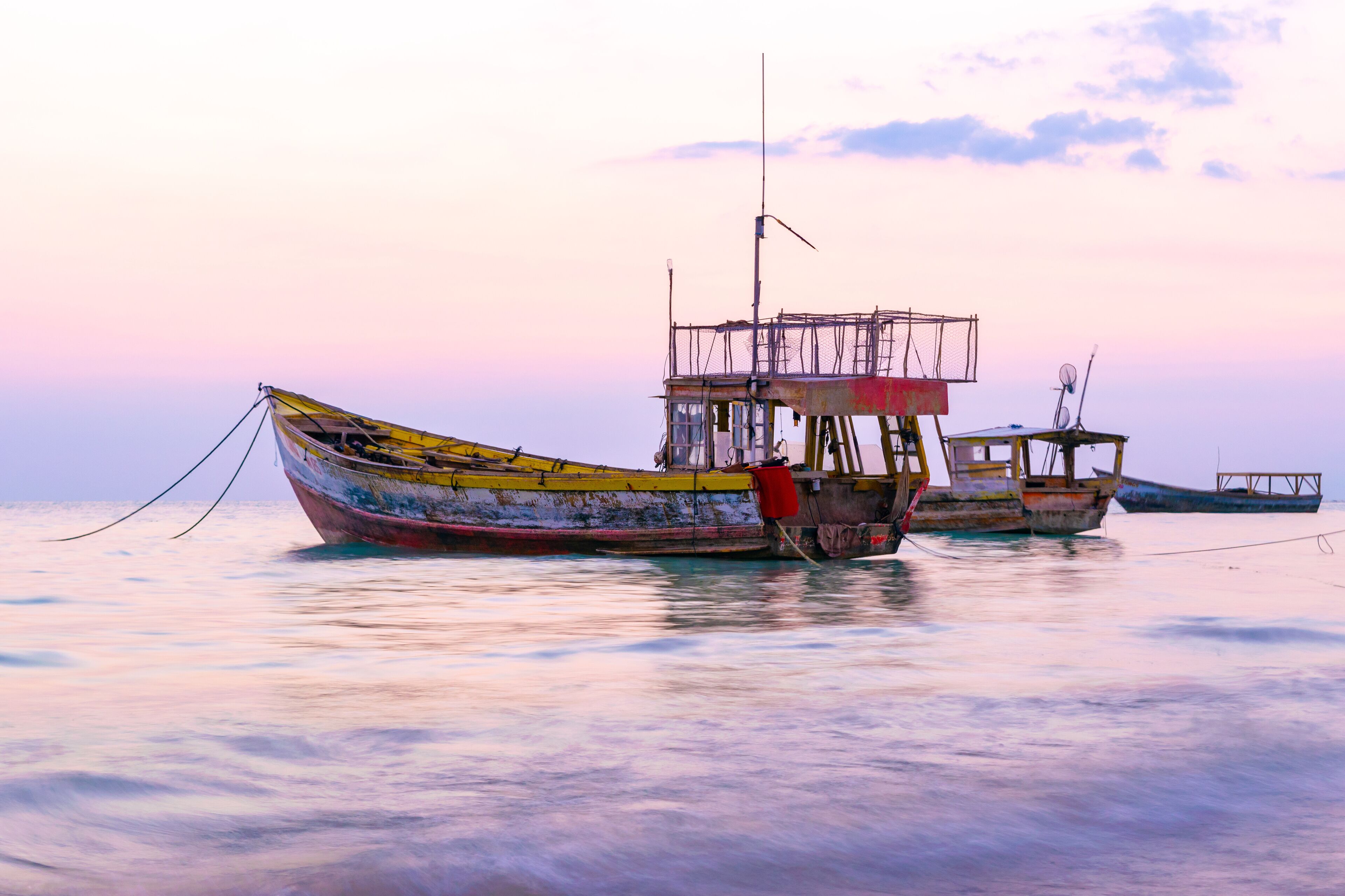 Colorful old wooden fishing boats floating near the coastline at sunset in Westmoreland, Jamaica