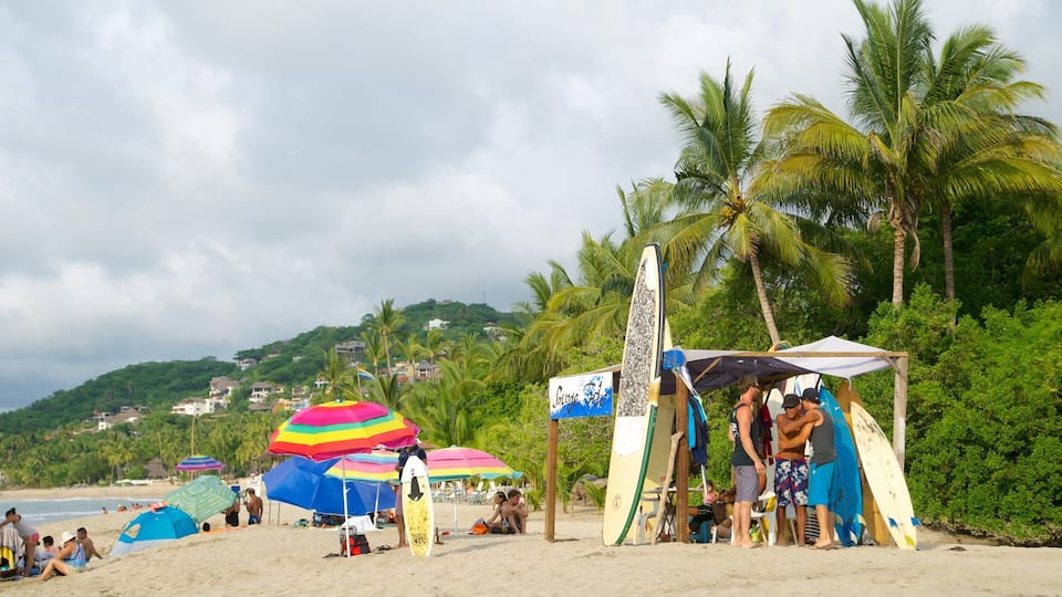 A beach with tents, surfboards, and colorful umbrellas.