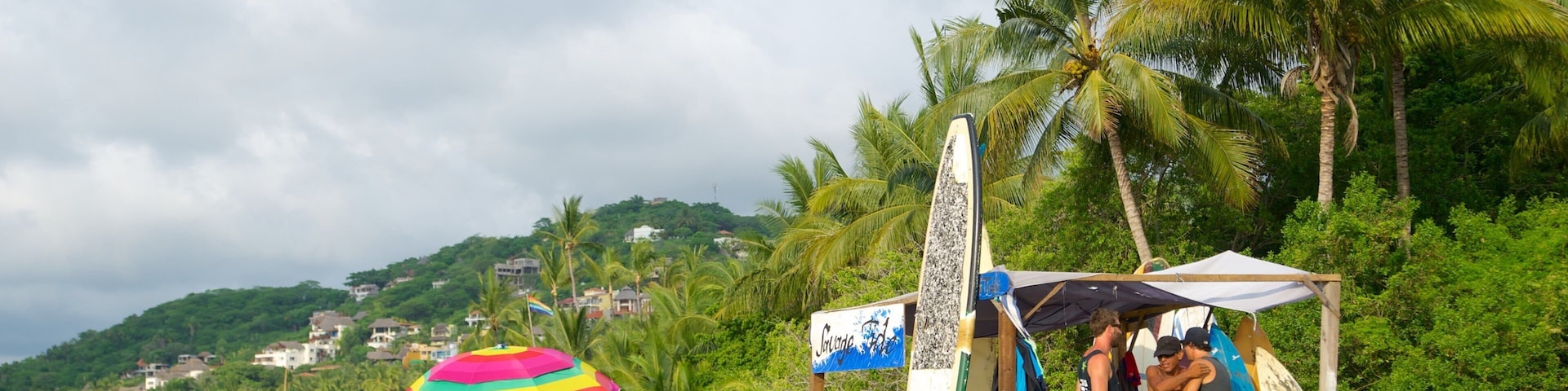 A beach with tents, surfboards, and colorful umbrellas.