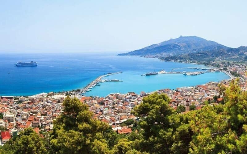 A coastal city with a mountain, a harbor, and a cruise ship.