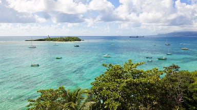 A turquoise sea with boats, a small island with a lighthouse, and a clear sky.