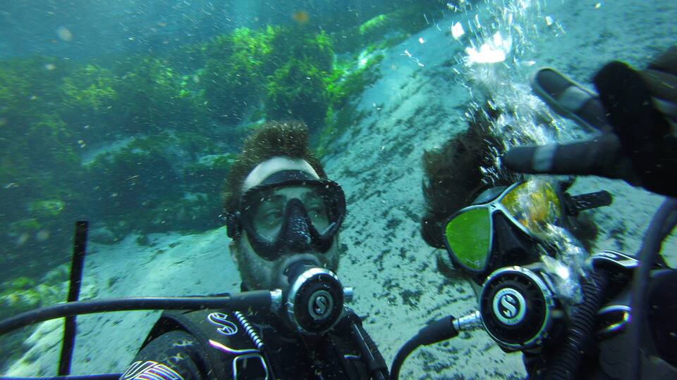 Two scuba divers underwater with bubbles rising to the surface.