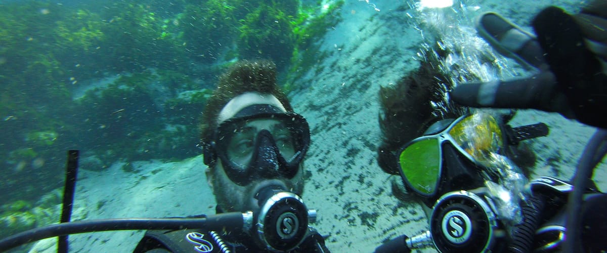 Two scuba divers underwater with bubbles rising to the surface.