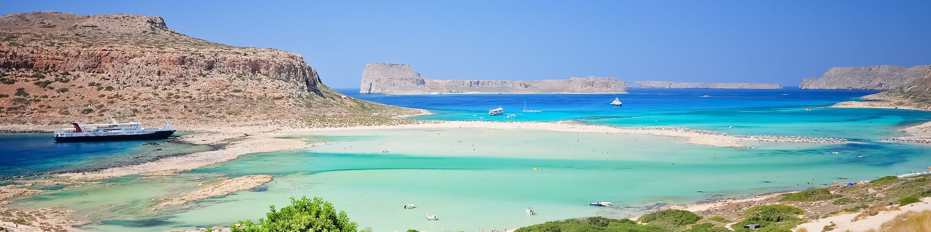 Un paisaje costero con aguas turquesas cristalinas, playas arenosas y acantilados rocosos.
