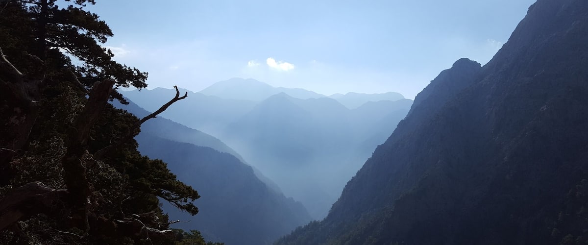 A mountainous landscape with dense forests and a clear sky.