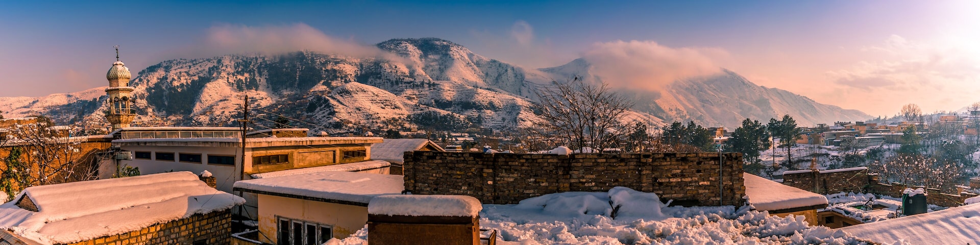 A snow-covered mountainous landscape with a mosque and residential buildings.