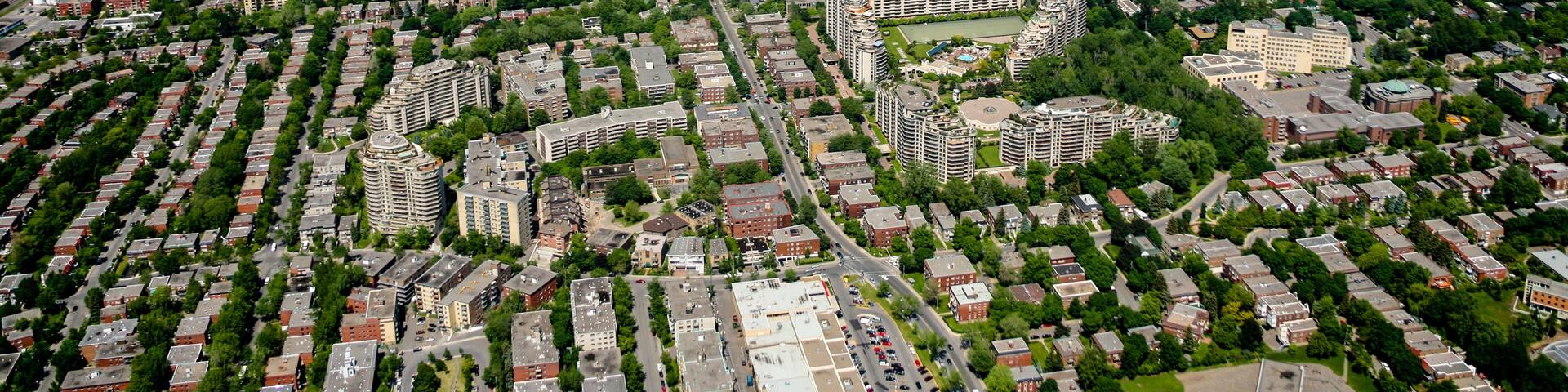An aerial view of a city with dense residential areas, several large buildings, and a river in the background.