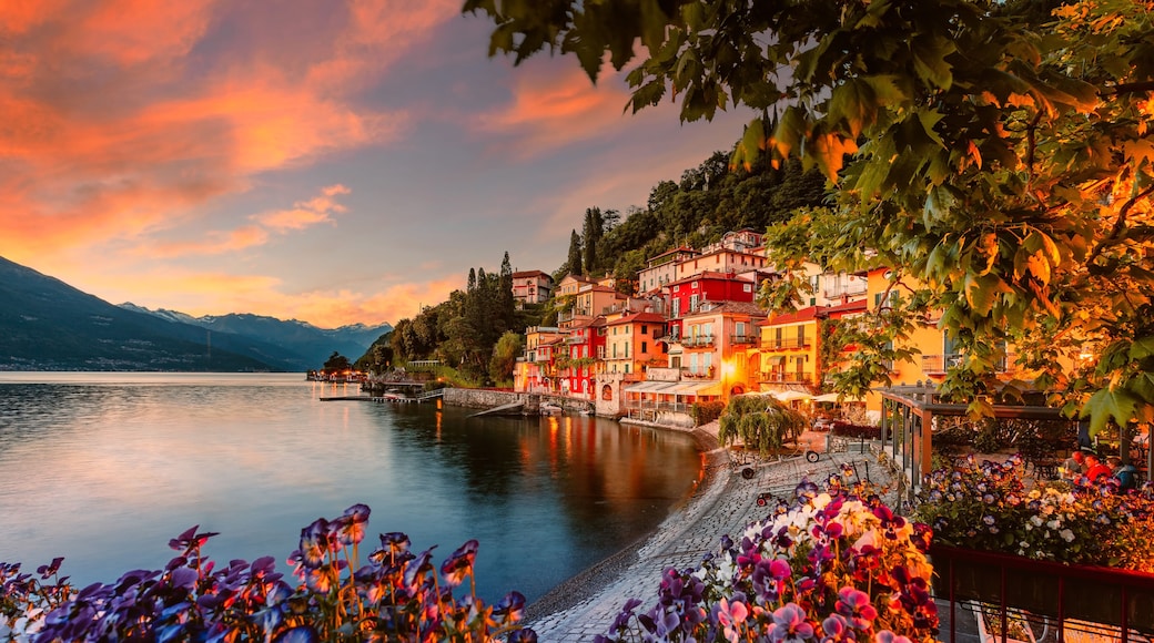 Village of Varenna on Lake Como at sunset with illuminated houses and colorful flowers in the foreground
