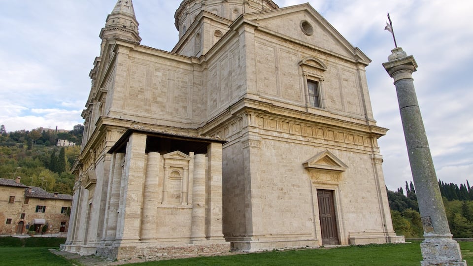 A historic stone church with a bell tower and a tall monument in front.