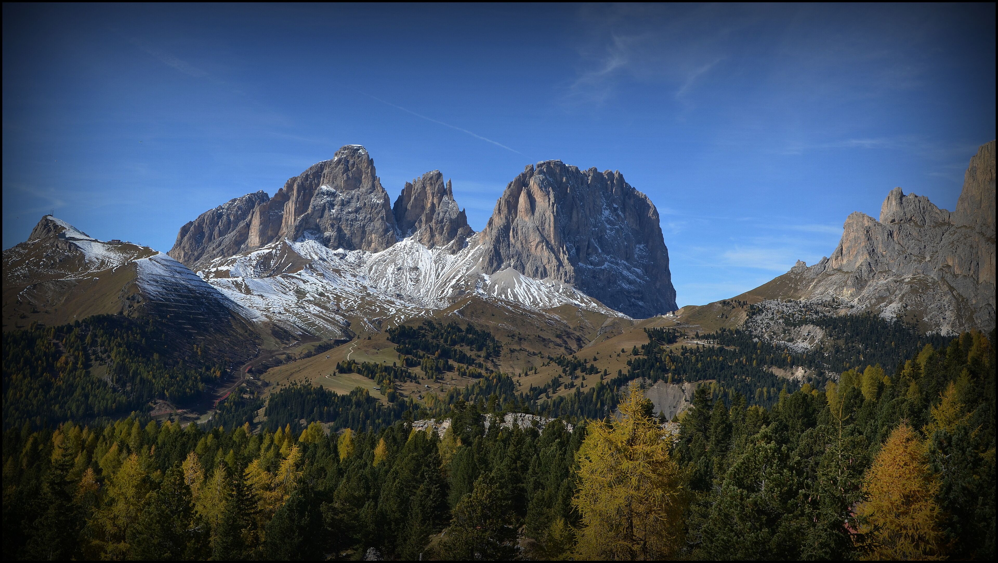 A mountain range with snow-capped peaks and dense forests.