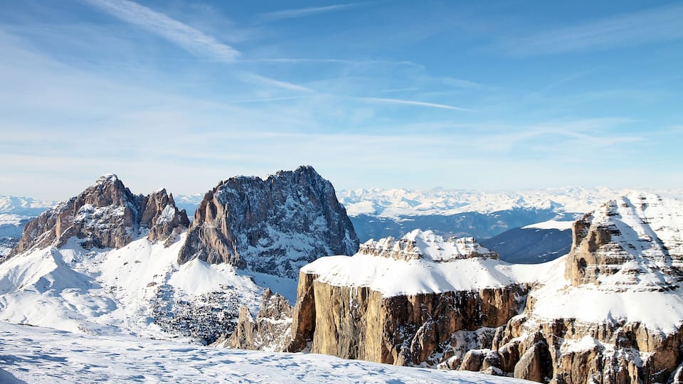 A snow-covered mountain range with sharp peaks and a clear blue sky.