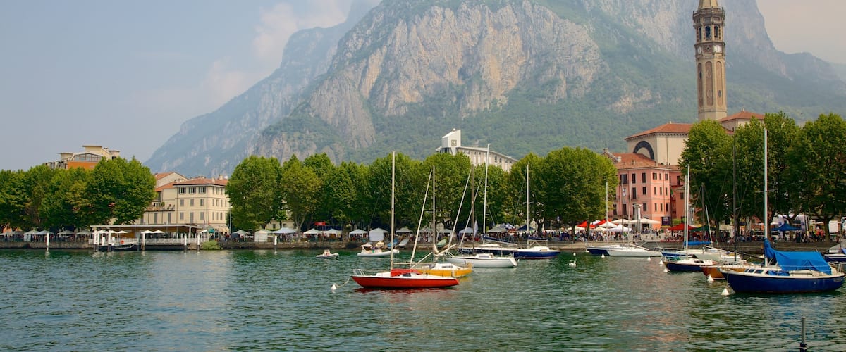 A harbor with boats, a clock tower, and a mountain in the background.