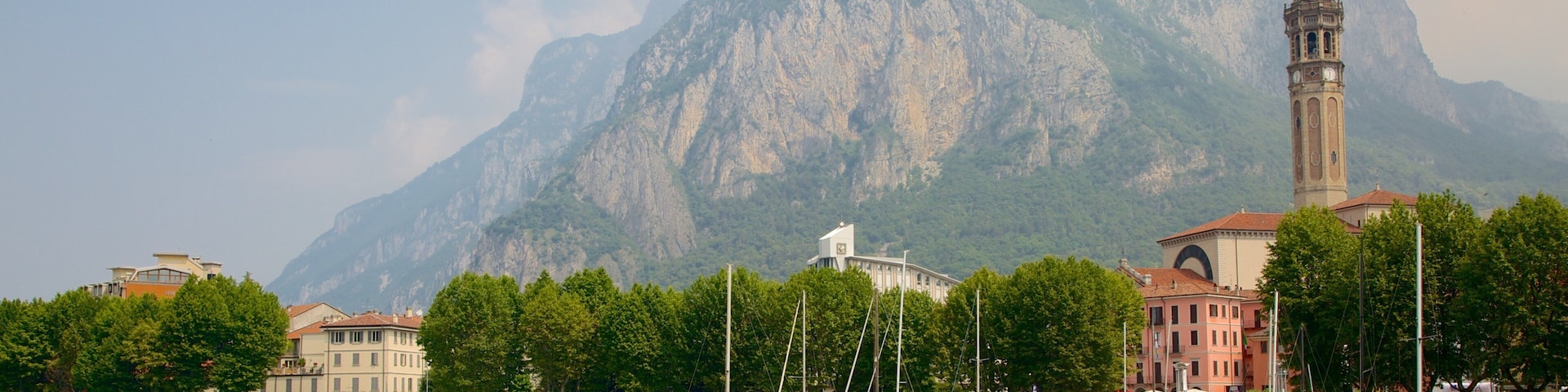A harbor with boats, a clock tower, and a mountain in the background.
