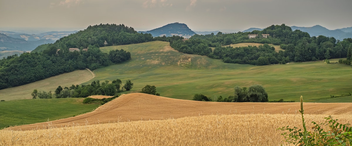 Rolling hills, a distant mountain, and a small building on a hill.