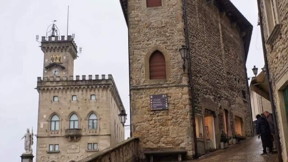 Un bâtiment en pierre doté d’une tour et de fenêtres en arc de cercle, un pont de pierre et une rue étroite.