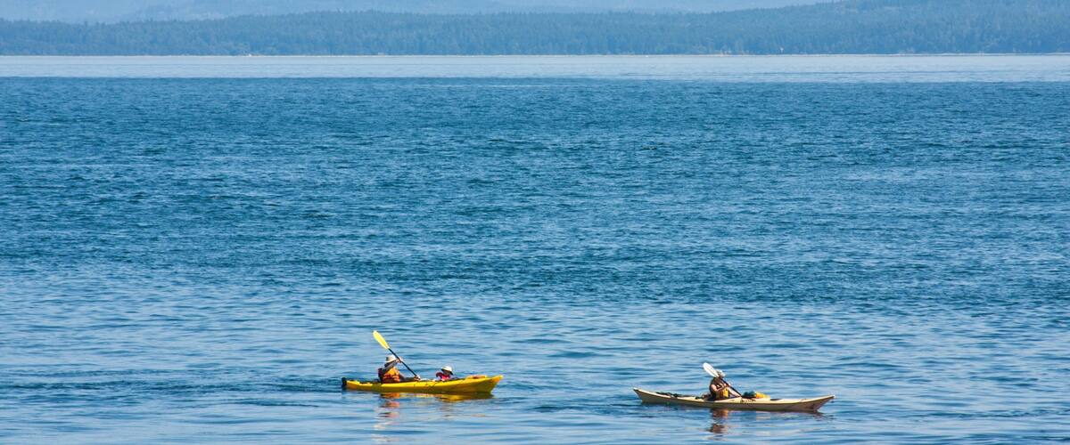 Two kayaks on a calm body of water with mountains in the background.